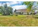 An expansive backyard with lush green grass and mature trees surrounding a tan brick home at 6686 Woodcrest Dr, Avon, IN 46123