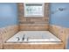 Bright bathroom showcasing a large soaking tub with tile surround and unique glass block window at 6686 Woodcrest Dr, Avon, IN 46123