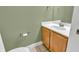 Neutral half-bathroom features a light wood vanity, white countertop, and green accent wall at 6686 Woodcrest Dr, Avon, IN 46123