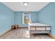 Well-lit bedroom with blue walls, wood laminate flooring, and a bright window at 6686 Woodcrest Dr, Avon, IN 46123