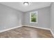 Serene bedroom featuring wood-look flooring and a bright window overlooking lush greenery at 6686 Woodcrest Dr, Avon, IN 46123