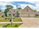 Charming two-story brick home featuring a well-manicured lawn, mature trees, and a three-car garage at 6686 Woodcrest Dr, Avon, IN 46123