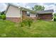Close-up of the home's brick and vinyl exterior featuring decorative flower beds on a sunny day at 7645 Inverness Dr, Indianapolis, IN 46237