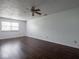 Spacious living room with dark hardwood floors, a ceiling fan, and natural light from a large window at 7645 Inverness Dr, Indianapolis, IN 46237