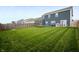 A wide view of a large backyard, showing a lush lawn, trampoline, fencing, and the home's rear at 77 Winding Brook Way, Pendleton, IN 46064