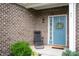 Home's welcoming blue front door and a cozy porch setting with a chair and decorative wreath at 77 Winding Brook Way, Pendleton, IN 46064