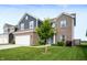 Two-story home featuring a brick-and-blue exterior, a two-car garage, and a tree in the front yard at 77 Winding Brook Way, Pendleton, IN 46064