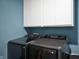 A laundry room featuring gray Samsung washer and dryer and white cabinets against blue walls at 77 Winding Brook Way, Pendleton, IN 46064