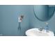Charming blue half-bathroom featuring a modern sink, round mirror and butterfly nightlight at 77 Winding Brook Way, Pendleton, IN 46064