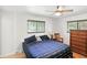 Cozy bedroom featuring a ceiling fan, wood floors, natural light, and a wooden dresser at 8219 Bishops Ln, Indianapolis, IN 46217