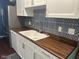 Updated kitchen boasts white cabinetry, wood countertops, stainless steel appliances, and patterned backsplash at 8540 E 37Th Pl, Indianapolis, IN 46226
