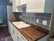 Updated kitchen featuring white cabinets, stainless steel appliances, wood countertops, and a patterned backsplash at 8540 E 37Th Pl, Indianapolis, IN 46226