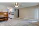 Open-concept living room featuring plush carpeting, ceiling fan, and adjacent kitchen at 8540 E 37Th Pl, Indianapolis, IN 46226