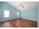 Bedroom with blue walls, laminate wood floors, a ceiling fan, and two windows at 8578 Nolan Dr, Fishers, IN 46038