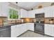 A kitchen featuring white cabinetry, stone backsplash, and stainless steel appliances under a vaulted ceiling at 10174 N County Road 471 E, Pittsboro, IN 46167