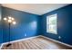 This bedroom features stylish blue walls and wood-look floors, complemented by a window and white trim at 10751 Sheffield Ct, Fishers, IN 46038
