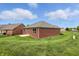 Backyard view of brick home featuring verdant lawn and mature trees, ideal for outdoor enjoyment at 1127 Kay Dr, Greenwood, IN 46142