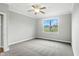 Bright bedroom with a ceiling fan, gray walls, white trim, plush carpet, and a large window overlooking the backyard at 1127 Kay Dr, Greenwood, IN 46142