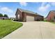 Brick home showcasing attached garage, long driveway, and verdant lawn under a blue sky at 1127 Kay Dr, Greenwood, IN 46142