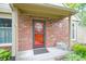 Close-up of the brick home's front entrance with a red door, small bench, and tidy landscaping at 11624 Buttonwood Dr, Carmel, IN 46033