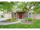 Charming brick home with mature trees, well-manicured lawn, and a welcoming red front door at 11624 Buttonwood Dr, Carmel, IN 46033