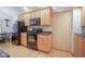 View of the kitchen with stainless appliances, wood cabinets, stone counters, and access door at 11624 Buttonwood Dr, Carmel, IN 46033