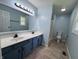 Bright bathroom featuring double sink vanity, tiled floors, and shower with glass door at 1206 Brownswood Dr, Brownsburg, IN 46112