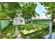 A peaceful backyard setting with a quaint outbuilding, green fence and mature trees at 2136 Ringgold Ave, Indianapolis, IN 46203