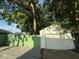 View of detached one car garage, green fence and a gravel driveway surrounded by mature trees at 2136 Ringgold Ave, Indianapolis, IN 46203