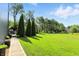 Expansive backyard featuring a lush lawn bordered by mature trees and manicured plants at 2227 Hidden Orchard Ct, Indianapolis, IN 46228