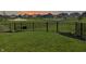 Backyard featuring a black aluminum fence, lush green grass, and community playground in the distance at sunset at 2232 Warbler St, Danville, IN 46122