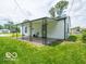 Backyard view features covered porch, small house with white siding and green grass at 3101 Gerrard Ave, Indianapolis, IN 46224