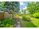 Lush backyard features a stone pathway, well manicured plants, a mature tree, and a quaint seating area at 317 Stoner Dr, Anderson, IN 46013