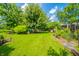 This expansive backyard has lush green grass, a swing, mature trees, and manicured landscaping at 317 Stoner Dr, Anderson, IN 46013