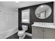 Renovated bathroom features a black accent wall, large round mirror, and modern fixtures at 329 Parkway Ave, Indianapolis, IN 46225