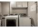 Bright laundry room with a side-by-side washer and dryer and overhead white storage cabinets at 350 N Meridian St # 606/607, Indianapolis, IN 46204