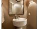 Elegant powder room featuring a stylish pedestal sink, decorative mirror, and modern sconce lighting at 350 N Meridian St # 606/607, Indianapolis, IN 46204