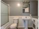 Clean and functional bathroom with a pedestal sink, toilet, and enclosed shower area at 3513 Ireland Dr, Indianapolis, IN 46235