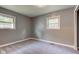 Small, basic bedroom with gray walls, neutral-colored carpet, and natural light streaming through two windows at 3513 Ireland Dr, Indianapolis, IN 46235