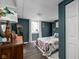 Basement bedroom with dark teal walls, wood flooring, and window with white curtains at 4901 N Kenwood Ave, Indianapolis, IN 46208