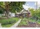 View of charming bungalow with beautiful landscaping including mature trees and a garden at 4901 N Kenwood Ave, Indianapolis, IN 46208