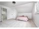 White carpeted attic bedroom with a pink bed, white walls, and an en-suite bathroom at 5144 N College Ave, Indianapolis, IN 46205