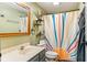 Cozy bathroom with green walls, a modern vanity, and a shower featuring a vibrant sunburst curtain at 5530 Pilgrim Dr, Indianapolis, IN 46254