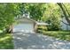 Traditional-style home featuring an attached two-car garage, a well-manicured lawn, and lush greenery in a suburban setting at 5530 Pilgrim Dr, Indianapolis, IN 46254