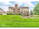 Grassy backyard with manicured lawn, mature trees, stone fire pit, and rear exterior of home at 5865 Osage Dr, Carmel, IN 46033