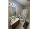 Bathroom featuring a shower-tub combo with neutral seashell wallpaper and brown vanity at 5954 Honeywell Dr, Indianapolis, IN 46236