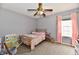 Bright bedroom with a ceiling fan, large window, and decorative pink curtains at 6126 Navy Cir, Indianapolis, IN 46221