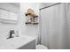 Neutral bathroom features a shower with striped curtain, floating shelves, and updated vanity at 6142 Evanston Ave, Indianapolis, IN 46220