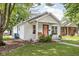 Charming one-story home features a quaint porch with swing, landscaped yard, and pink front door at 6142 Evanston Ave, Indianapolis, IN 46220