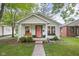 Charming single-story home featuring a inviting porch swing, lush landscaping, and a delightful coral front door at 6142 Evanston Ave, Indianapolis, IN 46220